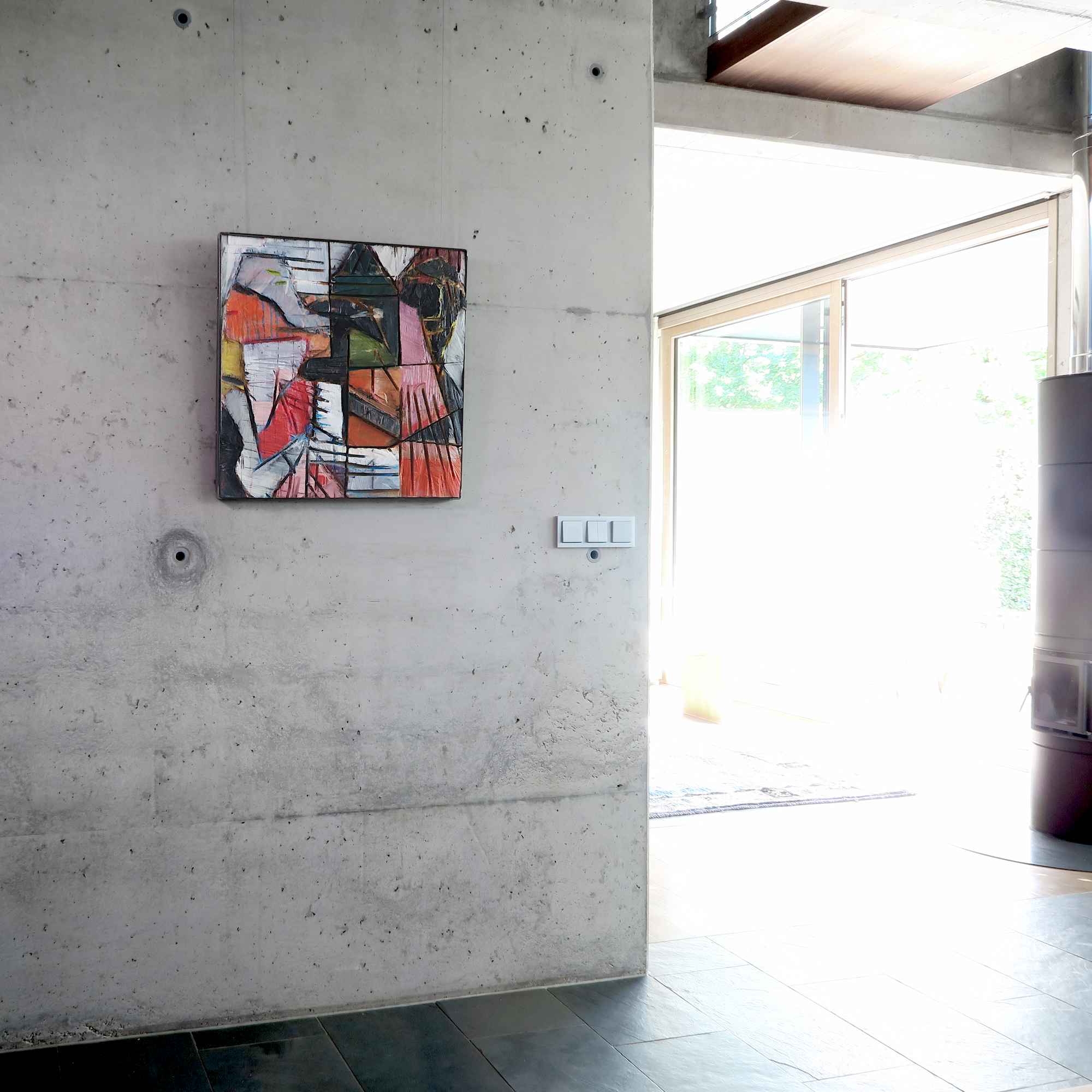 Holzbild mit dem Titel 'Heimweh nach gestern' an einer Betonwand in einem modernen Wohnhaus