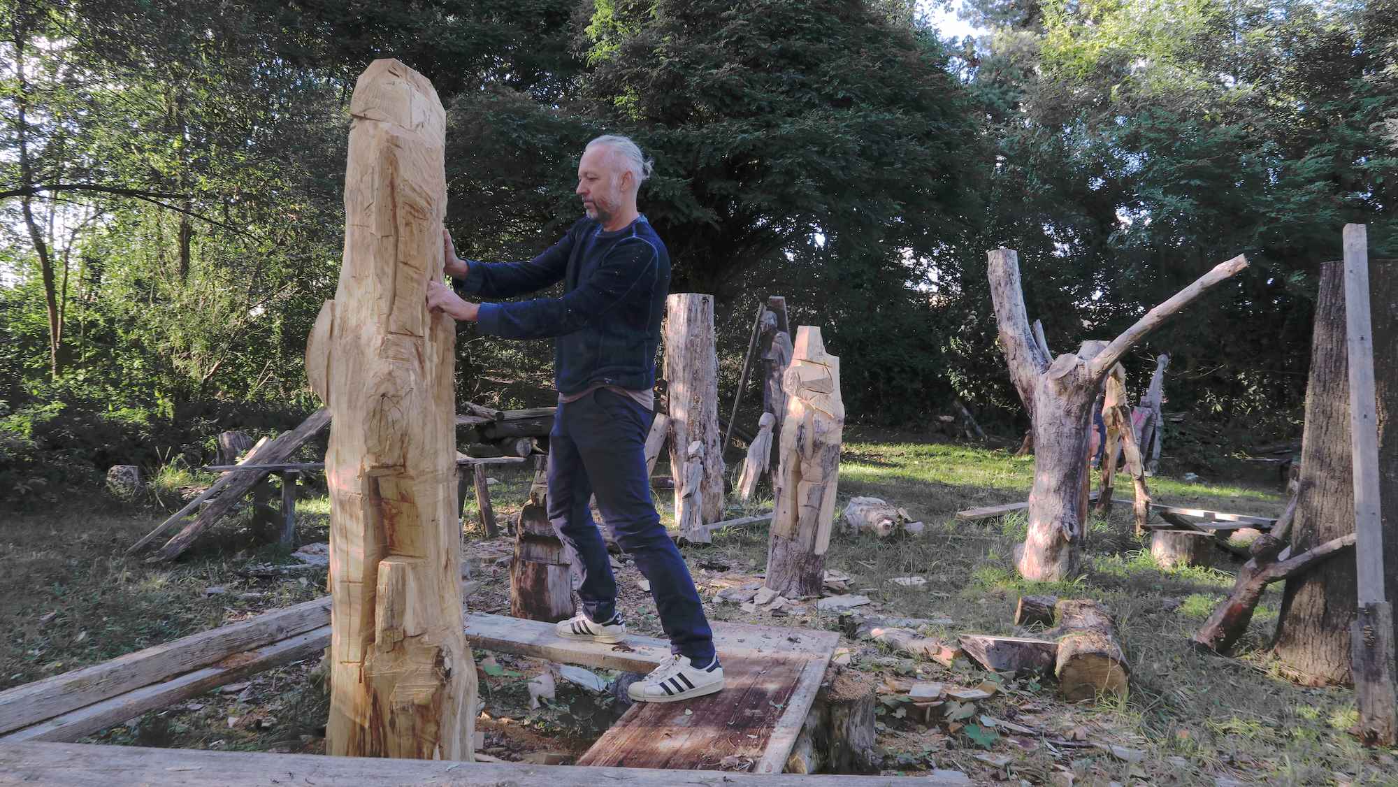 Holzbildhauer Klaus Schwendner auf einem Gerüst vor einer Holzskulptur auf seinem Schnitzplatz in Abensberg Bayern