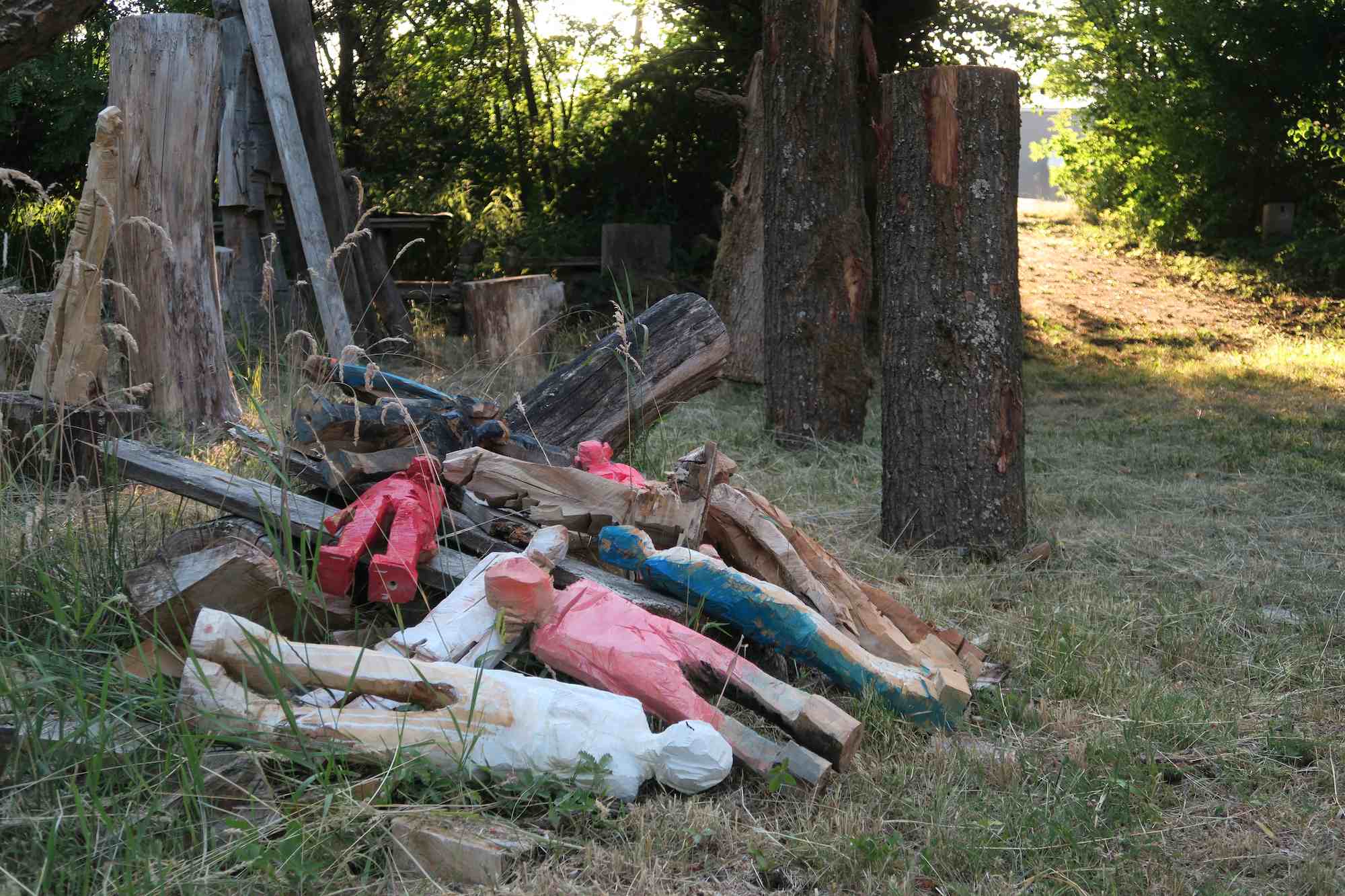 mehrere kleine Holzskulpturen liegen auf einem Haufen am Boden in der Natur