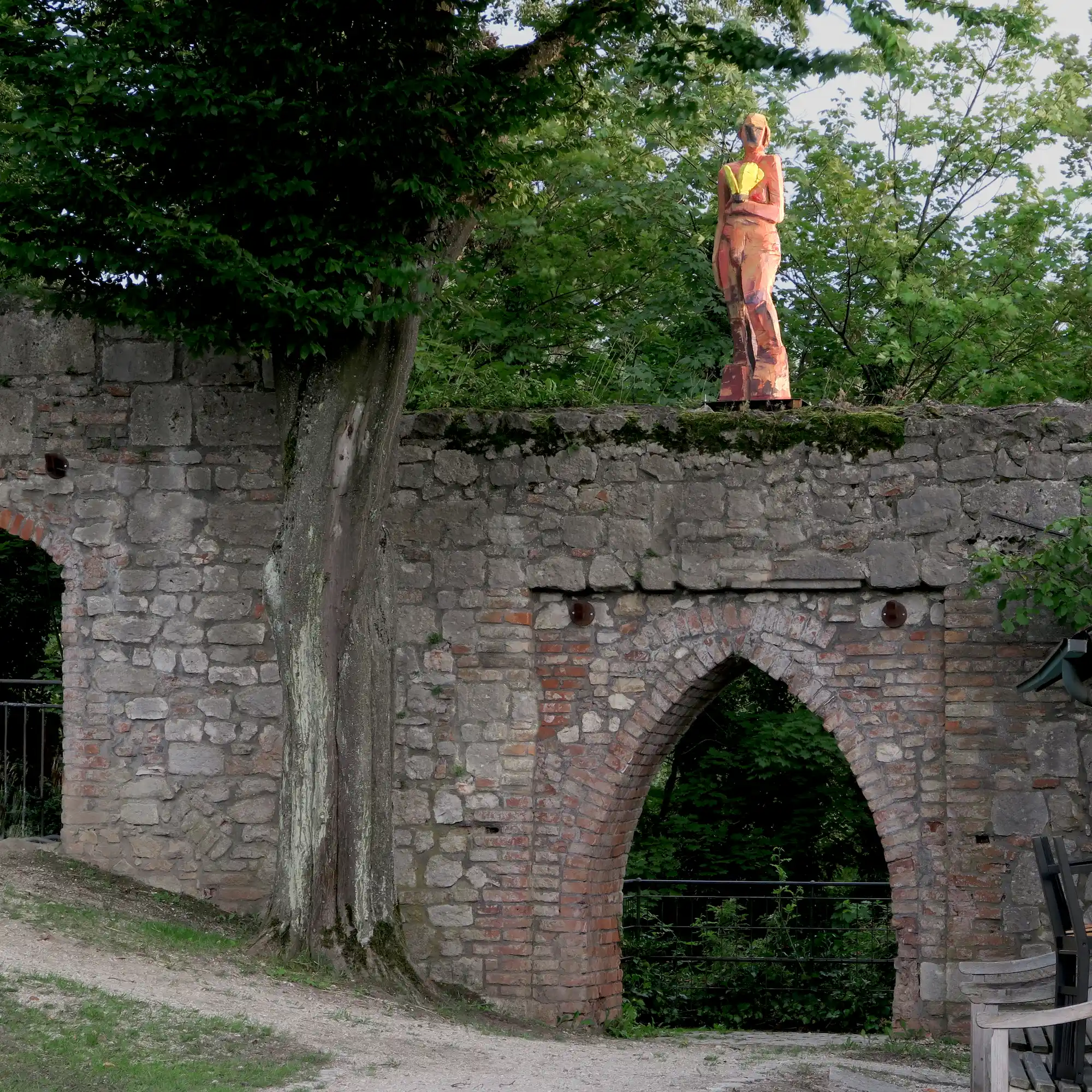 Holzskulptur 'Davina' mit gelbem Schmetterling auf der alten Stadtmauer im Schlossgarten in Abensberg
