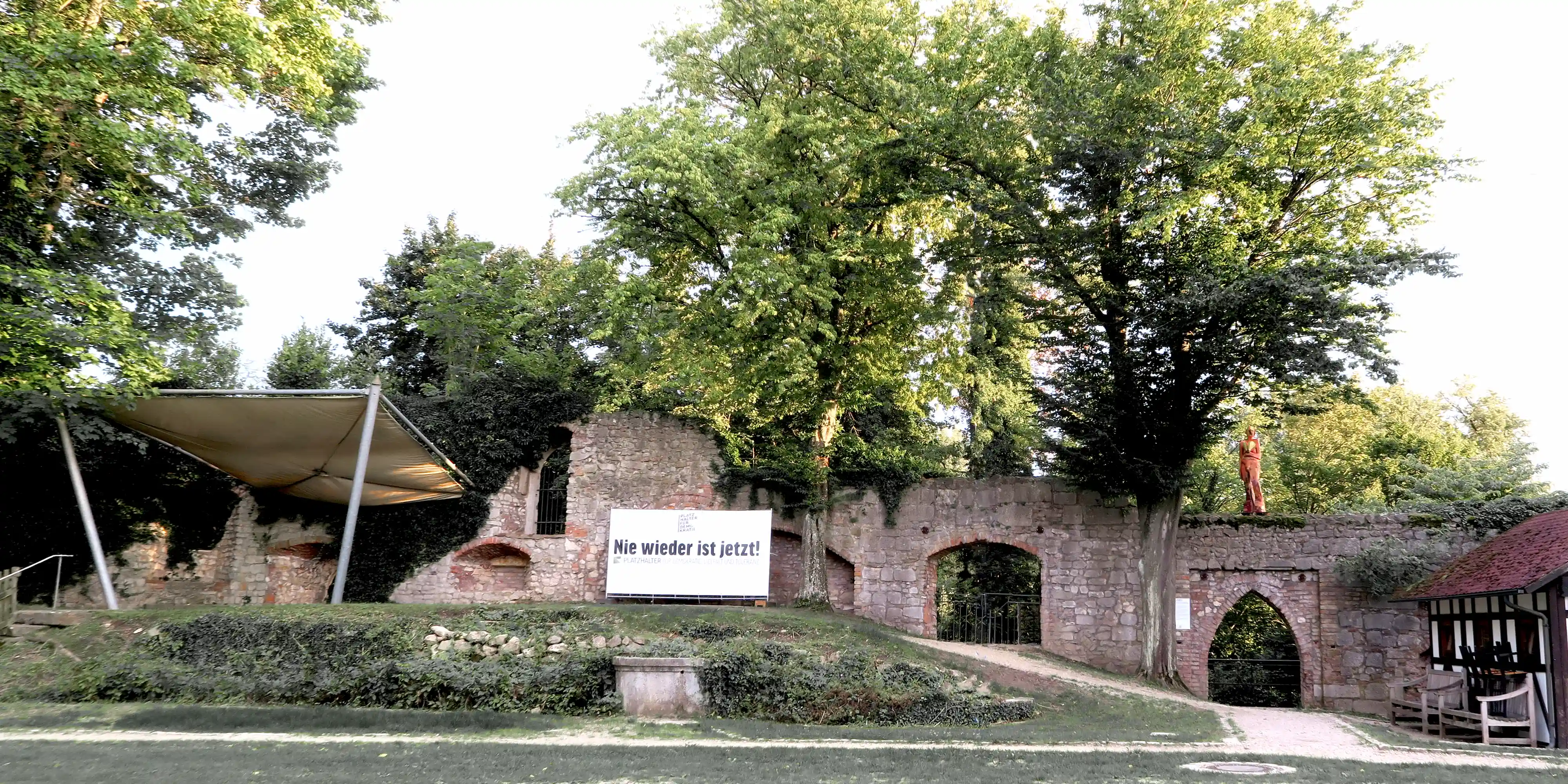 Holzskulptur 'Davina' mit gelbem Schmetterling auf der alten Stadtmauer im Schlossgarten in Abensberg